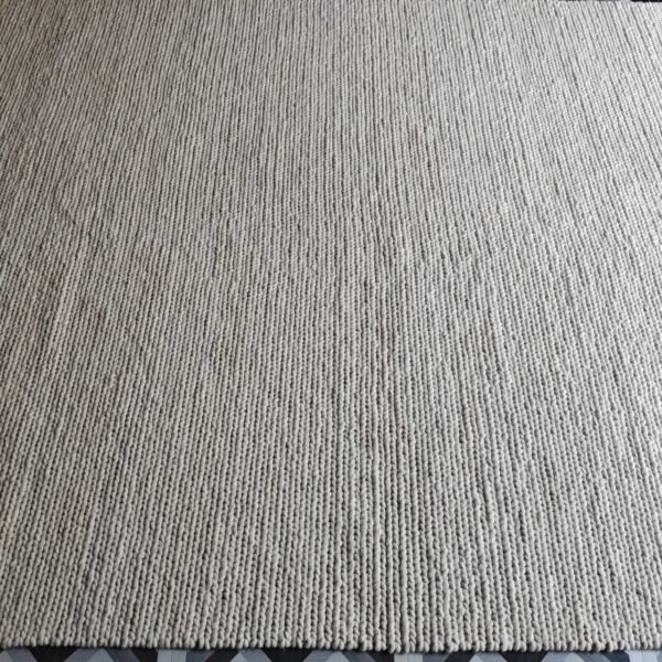 Modern handwoven wool rug in light grey with a textured surface for minimalist interiors.